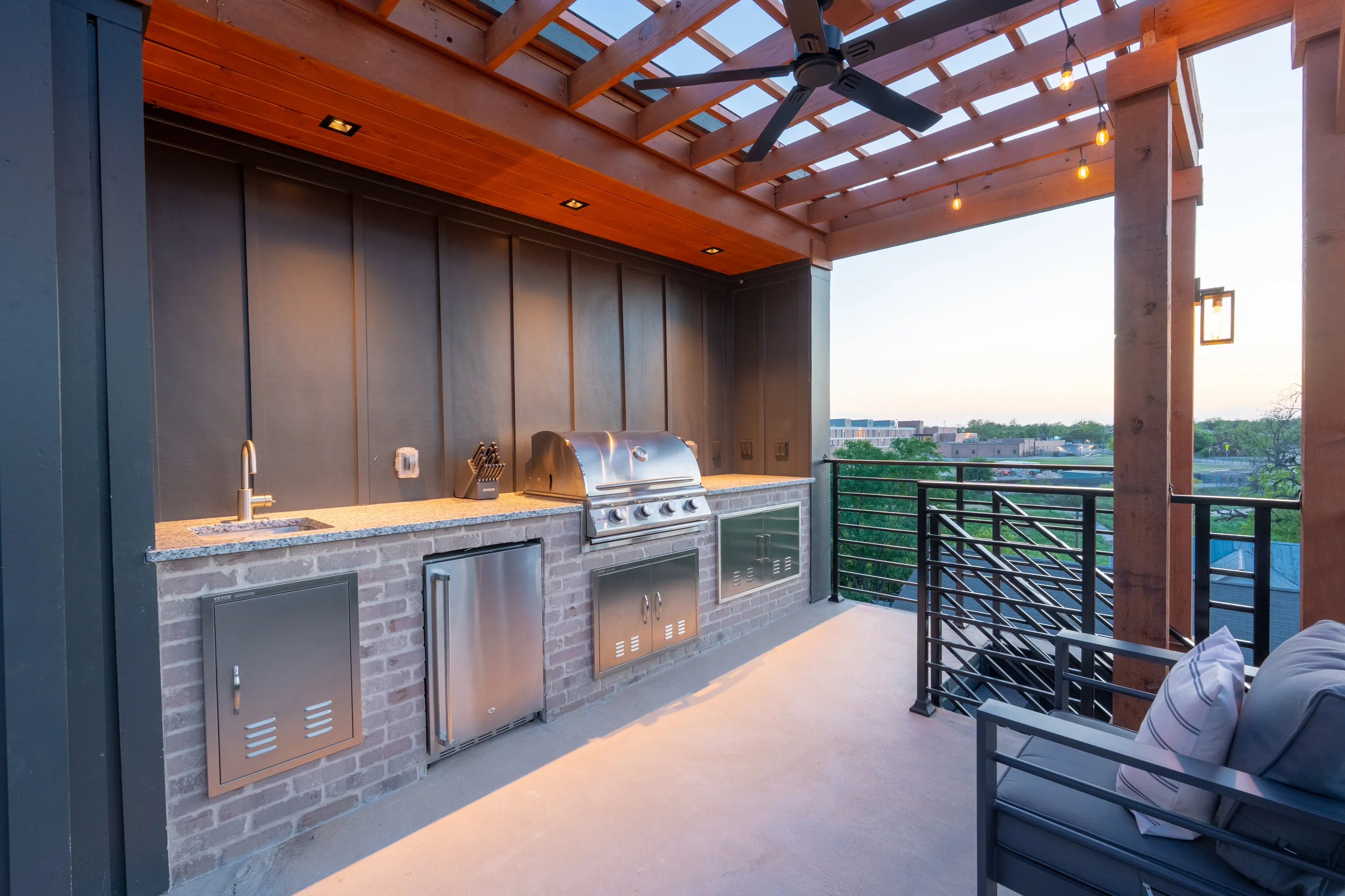 Covered outdoor kitchen and patio of an Ella Bree custom home at dusk.